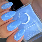 Hand with blue nail polish holding a bottle of 'Luna' nail polish.