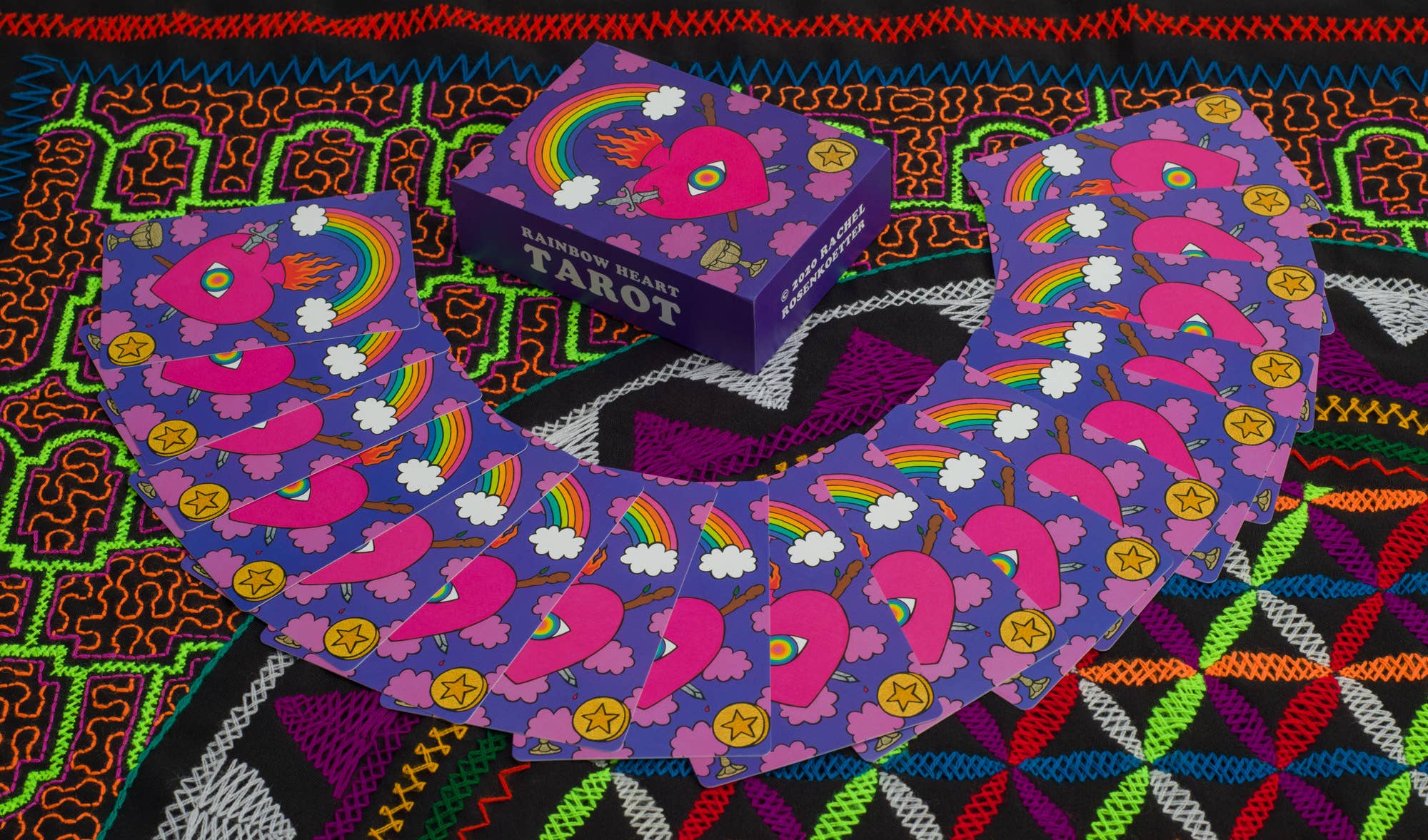 Colorful tarot card set with rainbow designs on a patterned fabric background