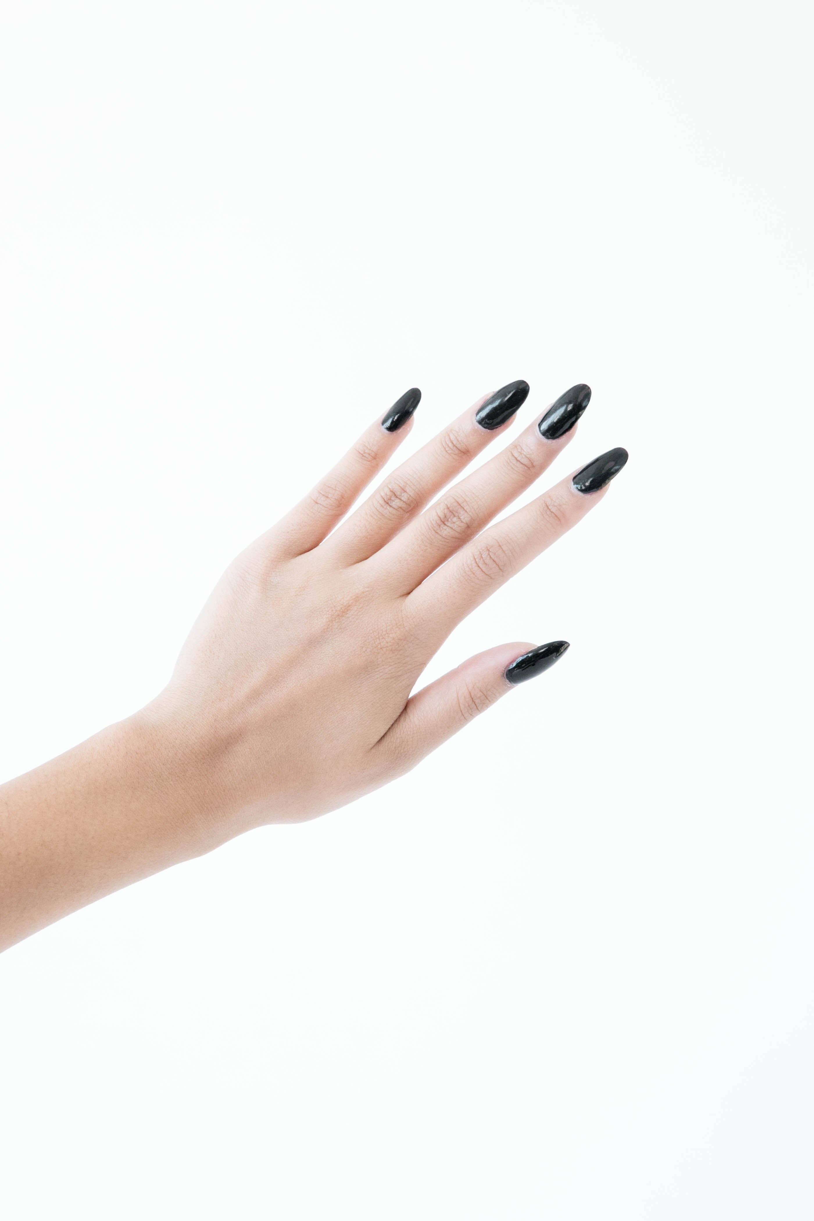 Hand with black nail polish on a white background