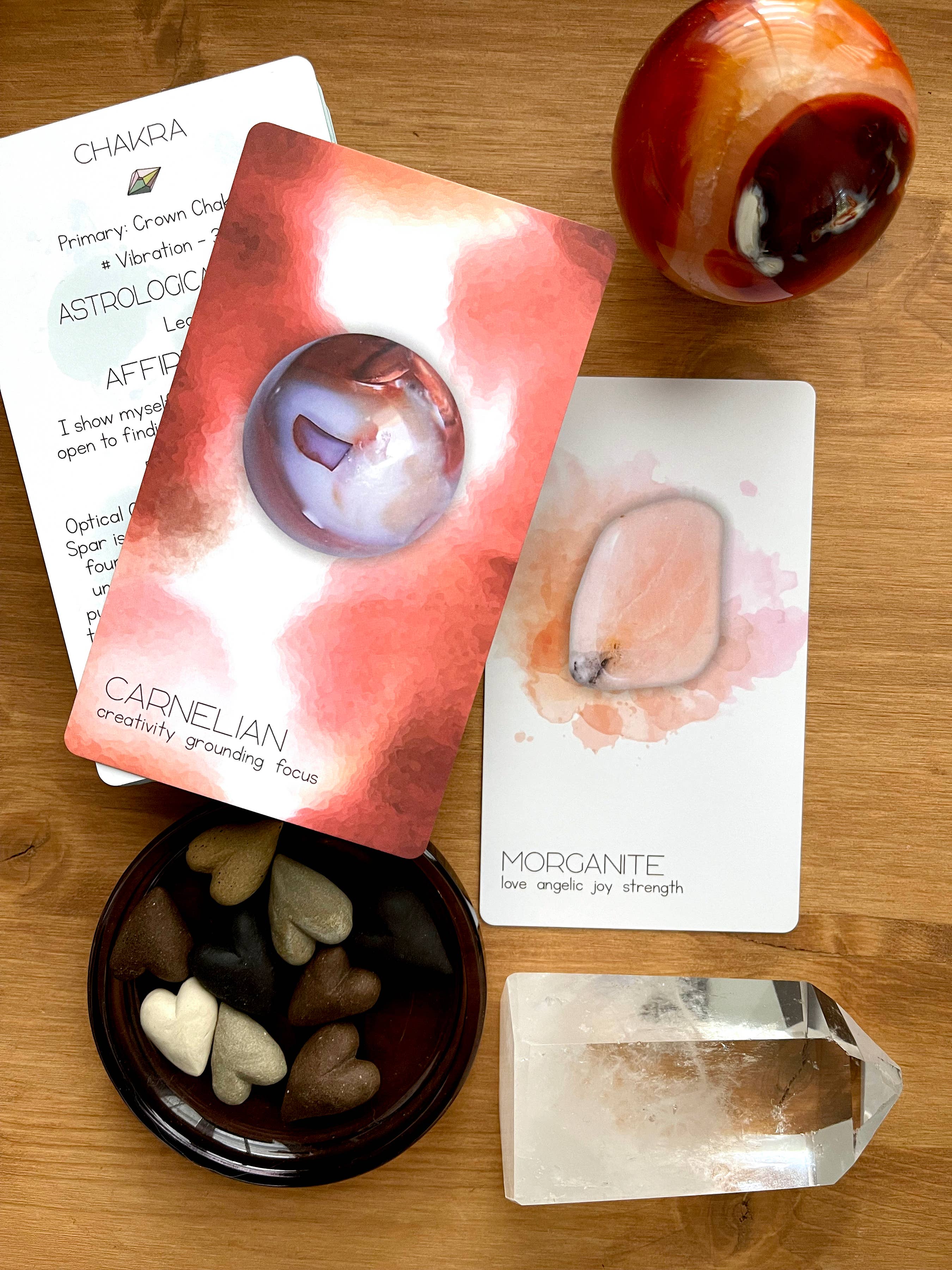 Collection of crystal-related items including cards, stones, and a crystal on a wooden surface.