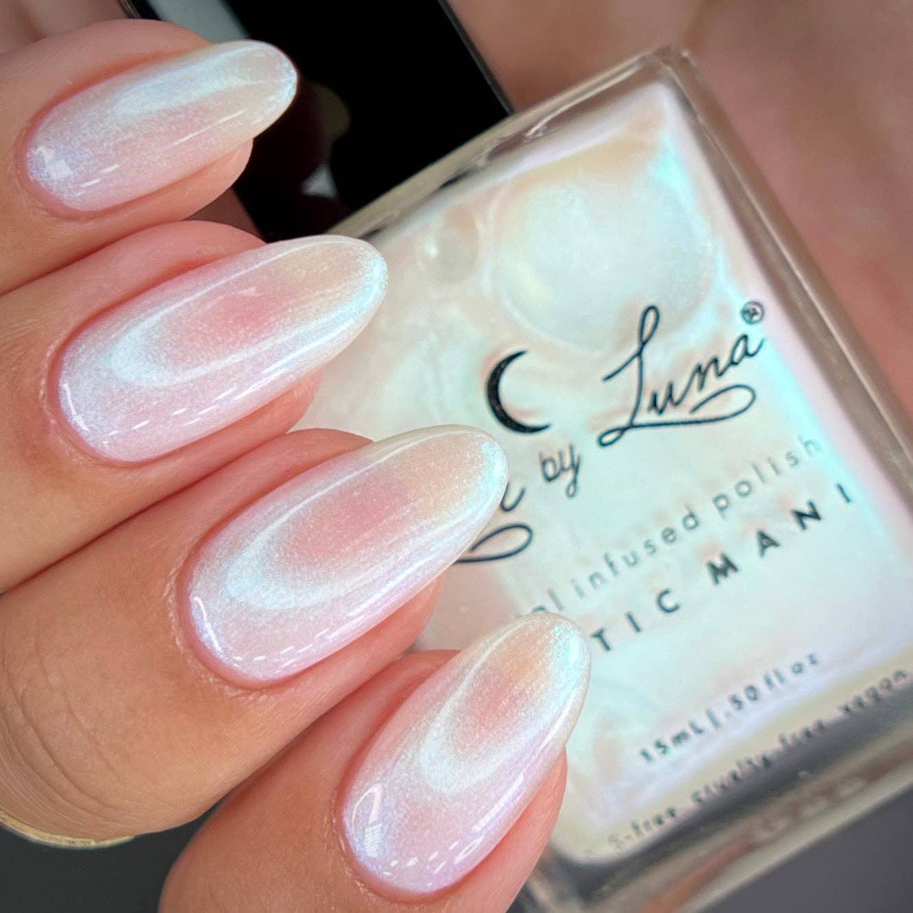 Nail polish with a hand displaying nails painted in a light pink color, and a clear bottle labeled 'Luna'.