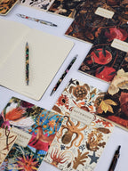 Collection of decorative notebooks and pens on a white surface