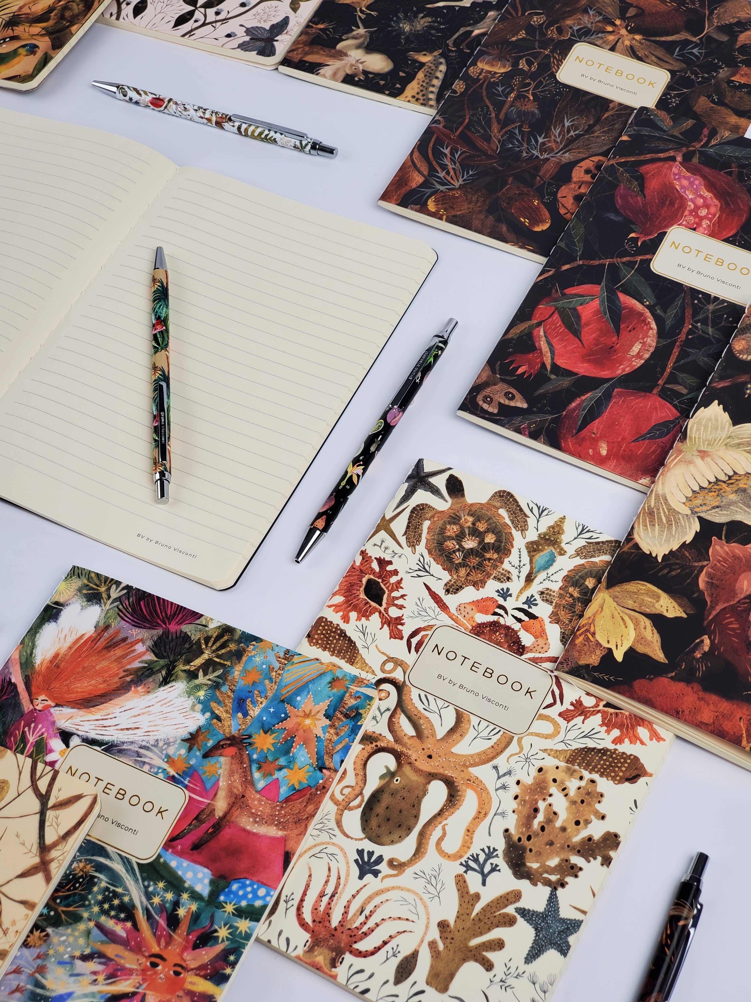 Collection of decorative notebooks and pens on a white surface