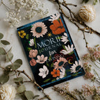 Decorative journal with floral design on a marble surface with flowers and branches.