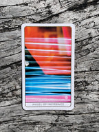 Colorful tarot card titled 'Angel of Incidence' on a wooden surface