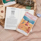 Tarot card featuring a couple on a beach with an open book and crystals in the background
