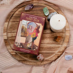 Cozy Witch Tarot Deck on a wooden surface with crystals and a candle