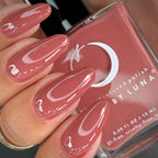 Nails with pink nail polish held next to a bottle of Luna nail polish.