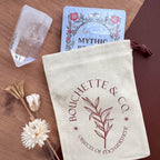 Bouchette & Co. pouch with cards and crystal on a wooden surface