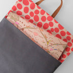 Tote bag with red polka dot pattern and floral design on a gray background