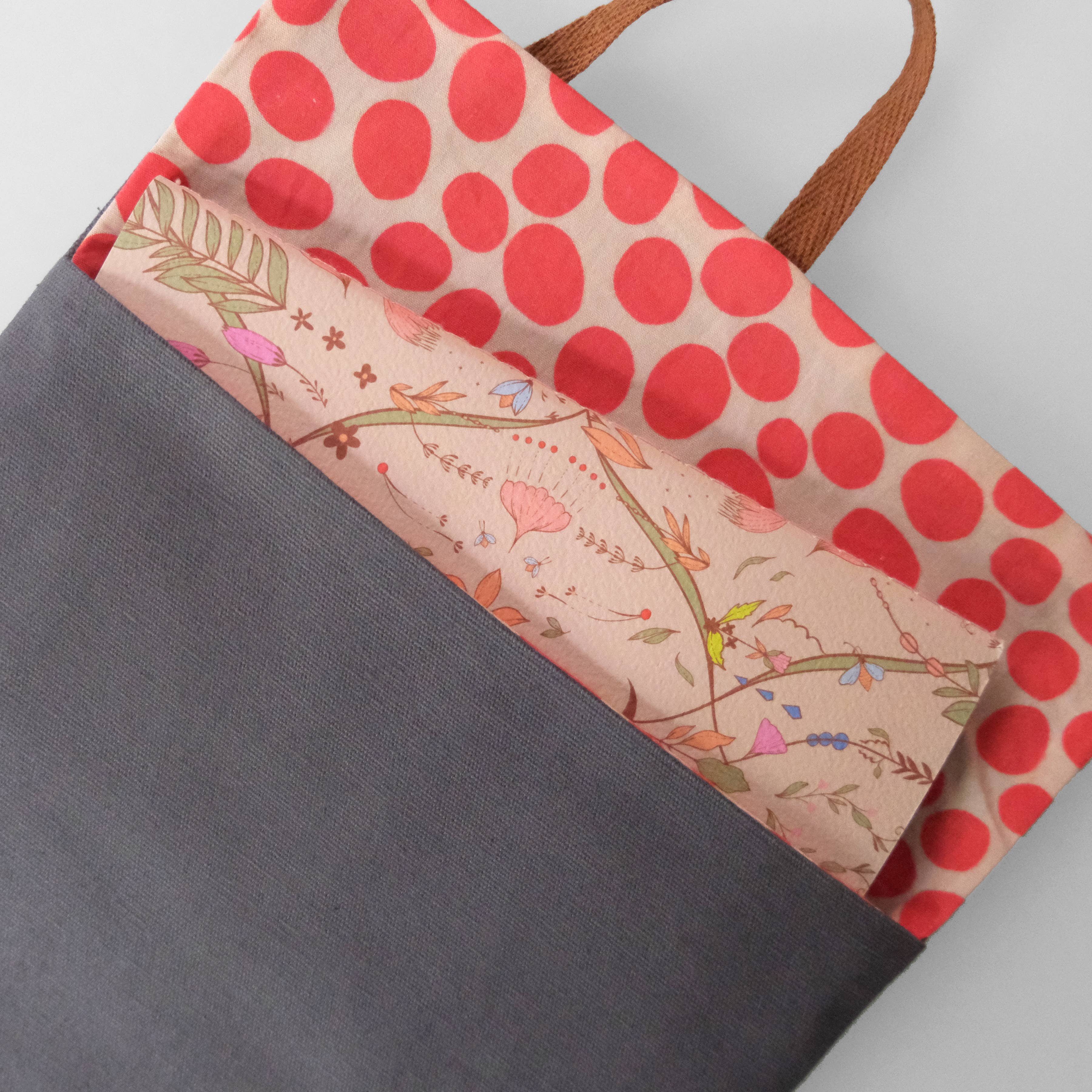 Tote bag with red polka dot pattern and floral design on a gray background