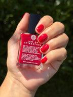 Hand holding a red bottle labeled 'Law of Attraction' against a blurred green background