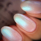 Close-up of a hand with iridescent nail polish on a blurred background