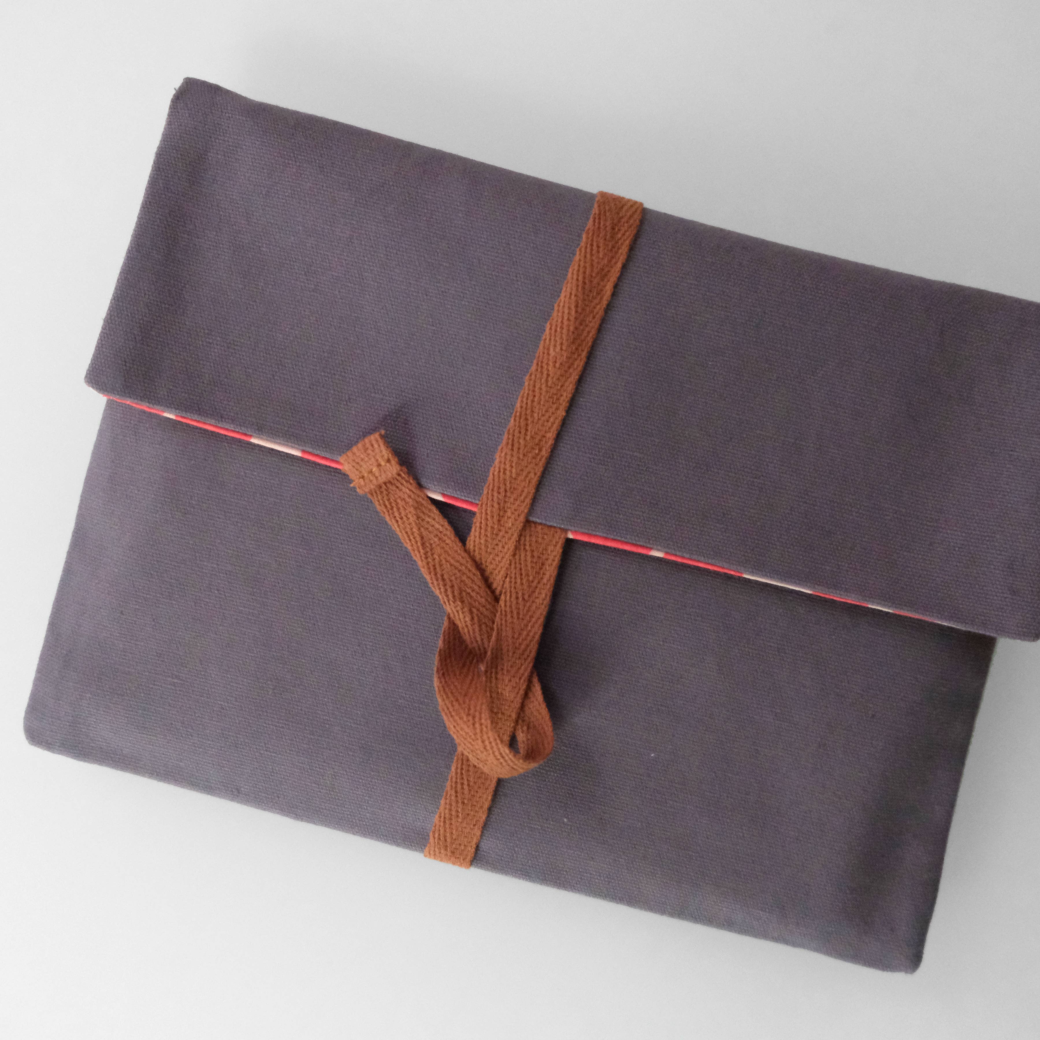 Gray fabric pouch with a brown strap on a white background
