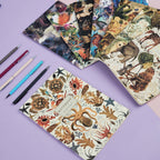 Assorted notebooks with animal-themed covers on a purple background with pens.