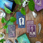 Collection of tarot cards on a wooden surface with plants and crystals.