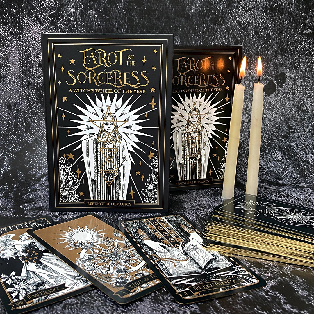 Tarot cards from 'Tarot of the Sorceress' with candles on a dark textured background