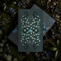 Card with floral design on a dark background surrounded by greenery