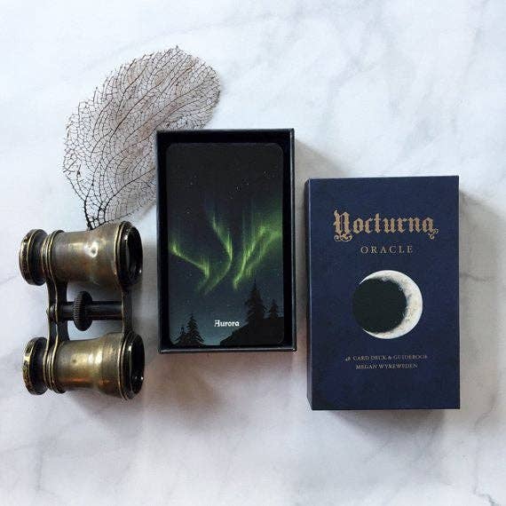 Nocturna Oracle card deck with binoculars and dried plant on a white background