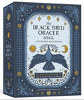 The Black Bird Oracle Deck box by Deborah Harkness, illustrated with a dark blue raven, stars, suns, and moons on a cream center panel, shown at a three-quarter angle against a white background.