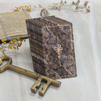 Decorative wooden box with intricate design, accompanied by a brass key on a light background.