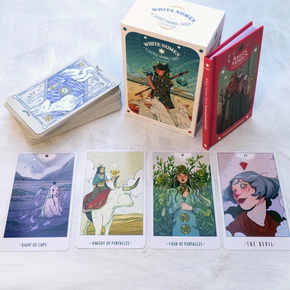 White Numinen tarot cards with a box and four card illustrations on a white surface.