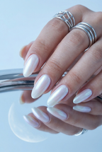 Close-up of a hand with white nail polish and silver rings on a light blue background