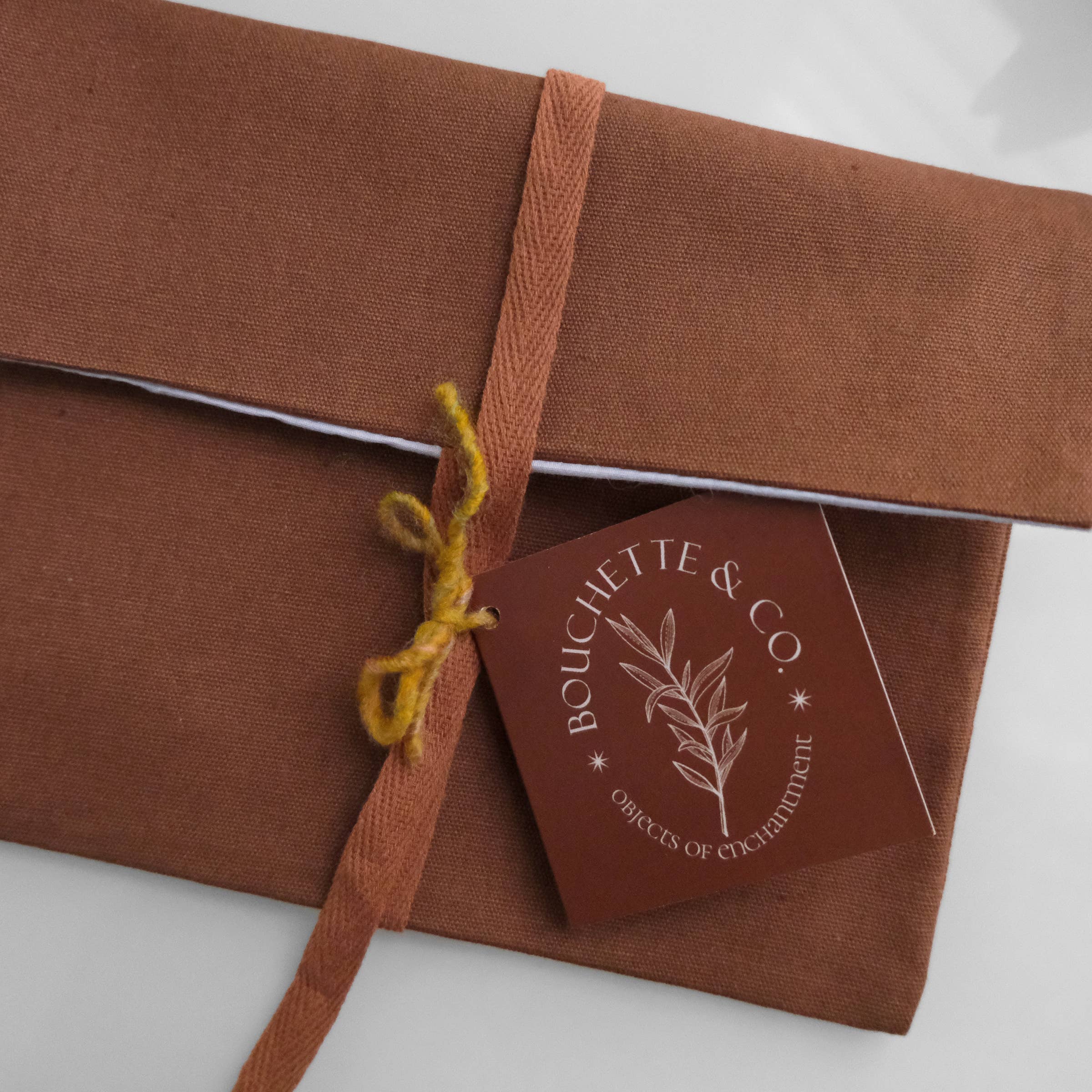Brown gift box with a ribbon and 'Bouchette & Co.' tag on a white background