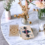 Playing cards with artistic designs on a marble table with decorative plants.
