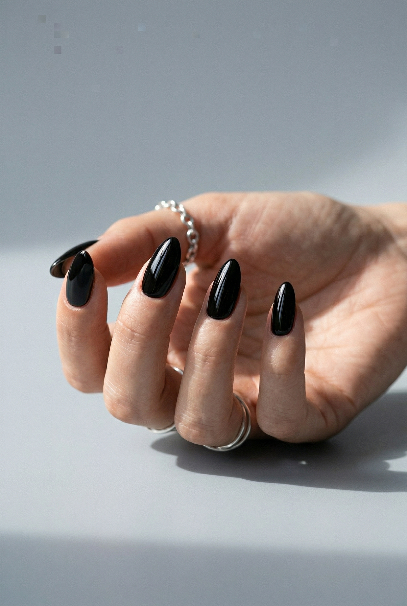 Hand with black nail polish on a gray background