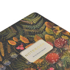 Notebook with a botanical design featuring leaves and mushrooms on a dark background.