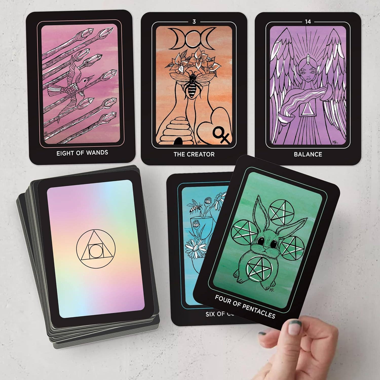 Collection of tarot cards with artistic designs on a light gray surface.