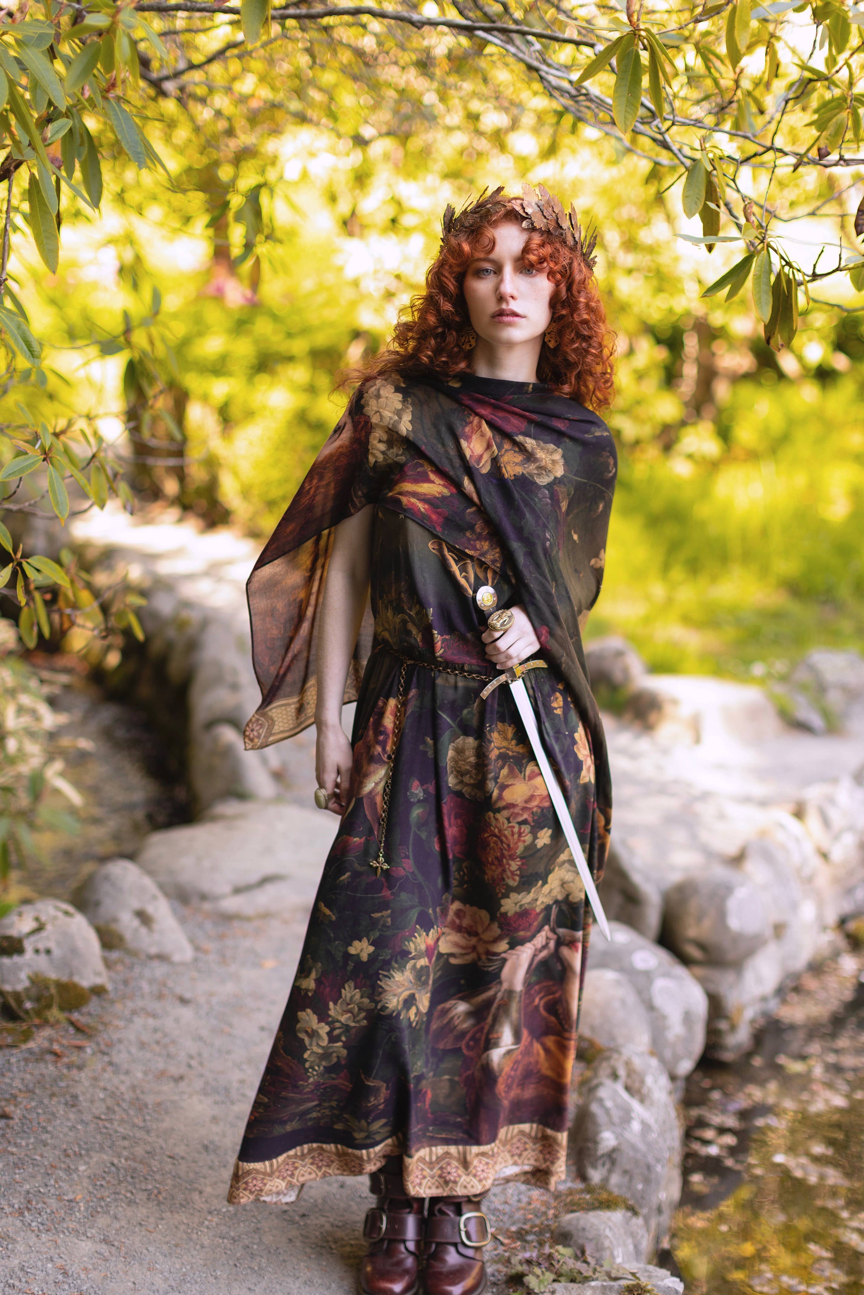 Person in a fantasy costume with a sword standing in a forest setting