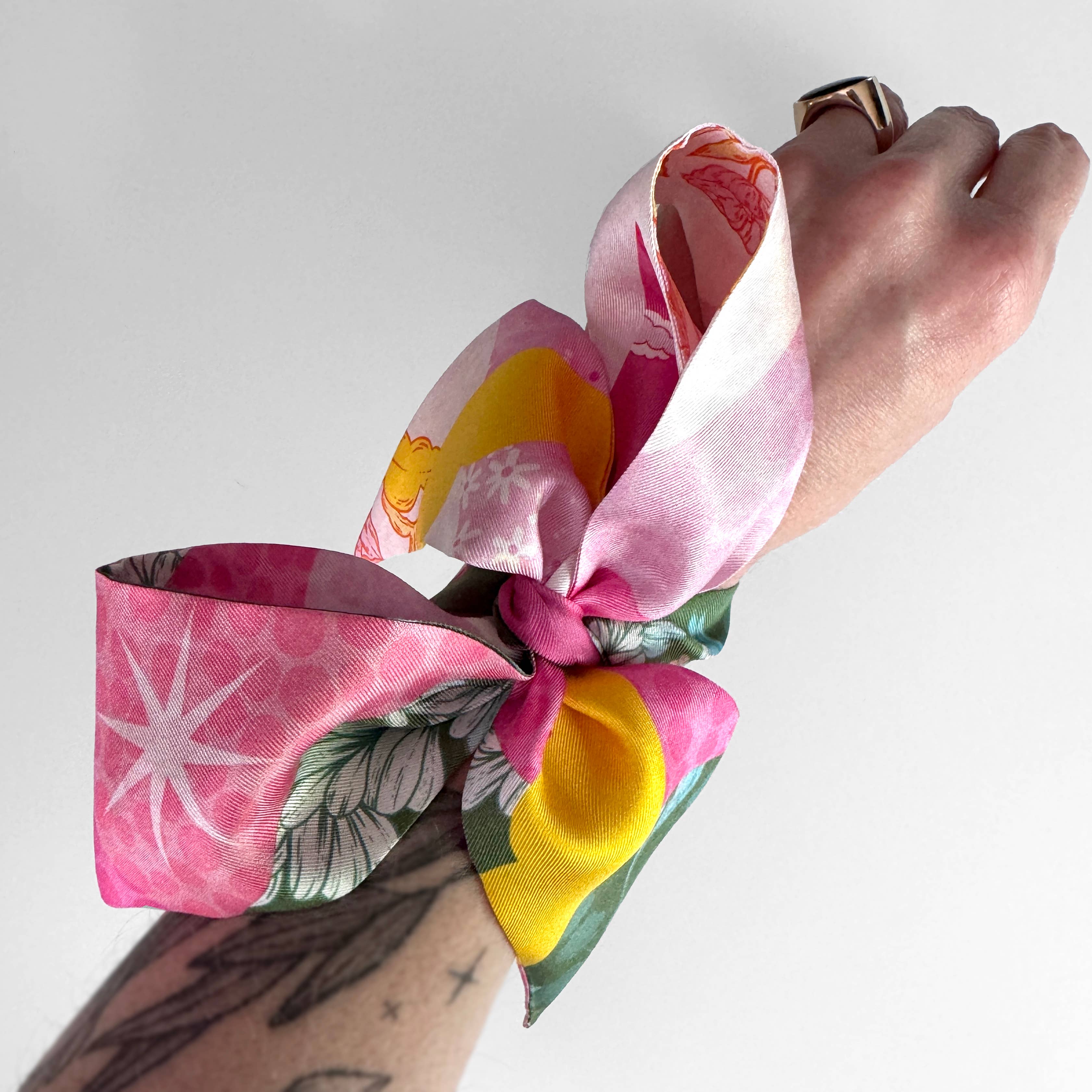 Hand holding a colorful floral headband against a white background