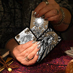 Person holding tarot cards with intricate designs on a dark background