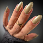 Hand with gold glittery nail polish on a dark background