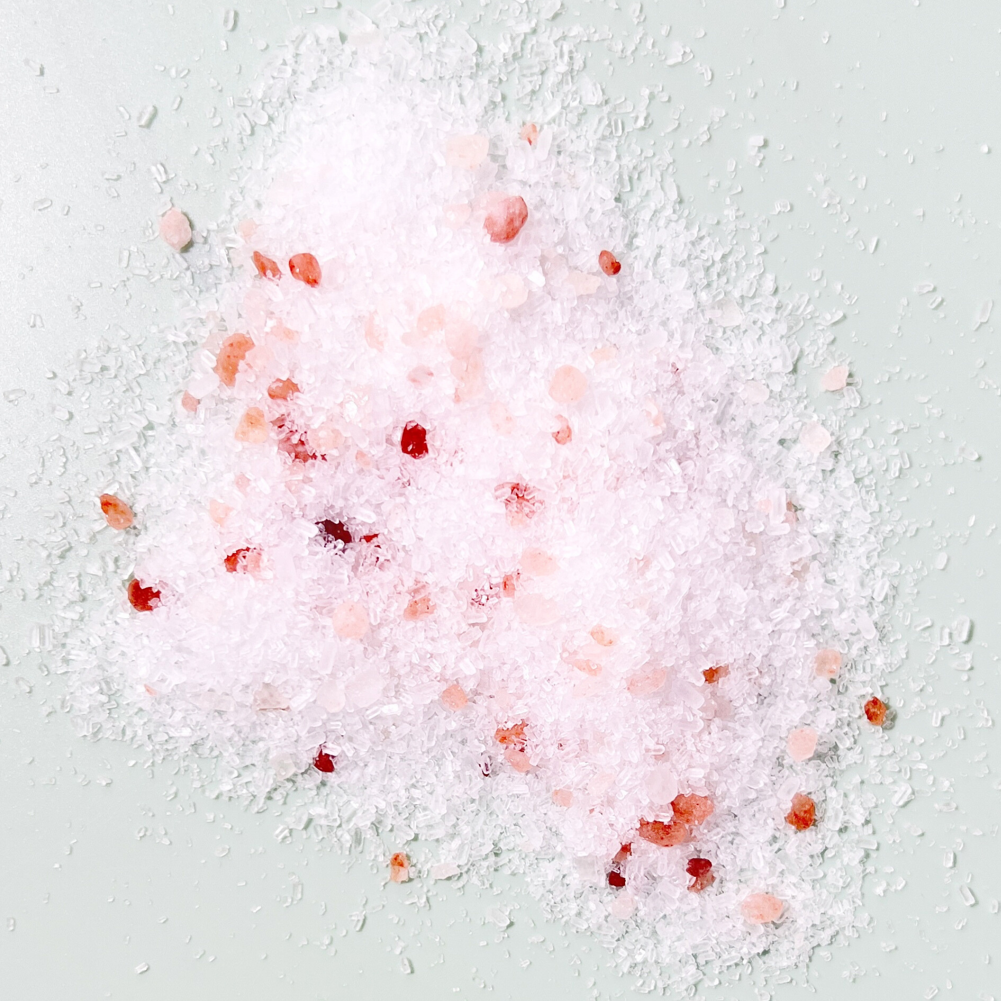 Pink bath salts with red flowers on a light gray background