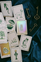 Collection of tarot cards with illustrations on a dark fabric background, accompanied by vintage keys.