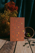 Notebook with decorative cover on a wooden surface with keys and plants.