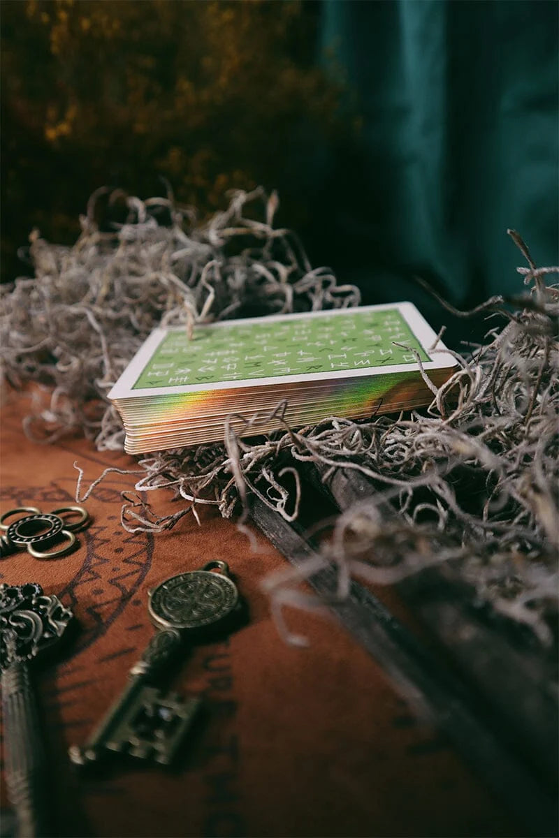 Green playing card on a textured surface with keys and spider webs