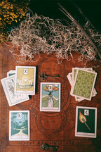 Tarot cards on a wooden surface with herbs and a key