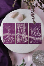 Three tarot cards on a round white surface with crystals and flowers.