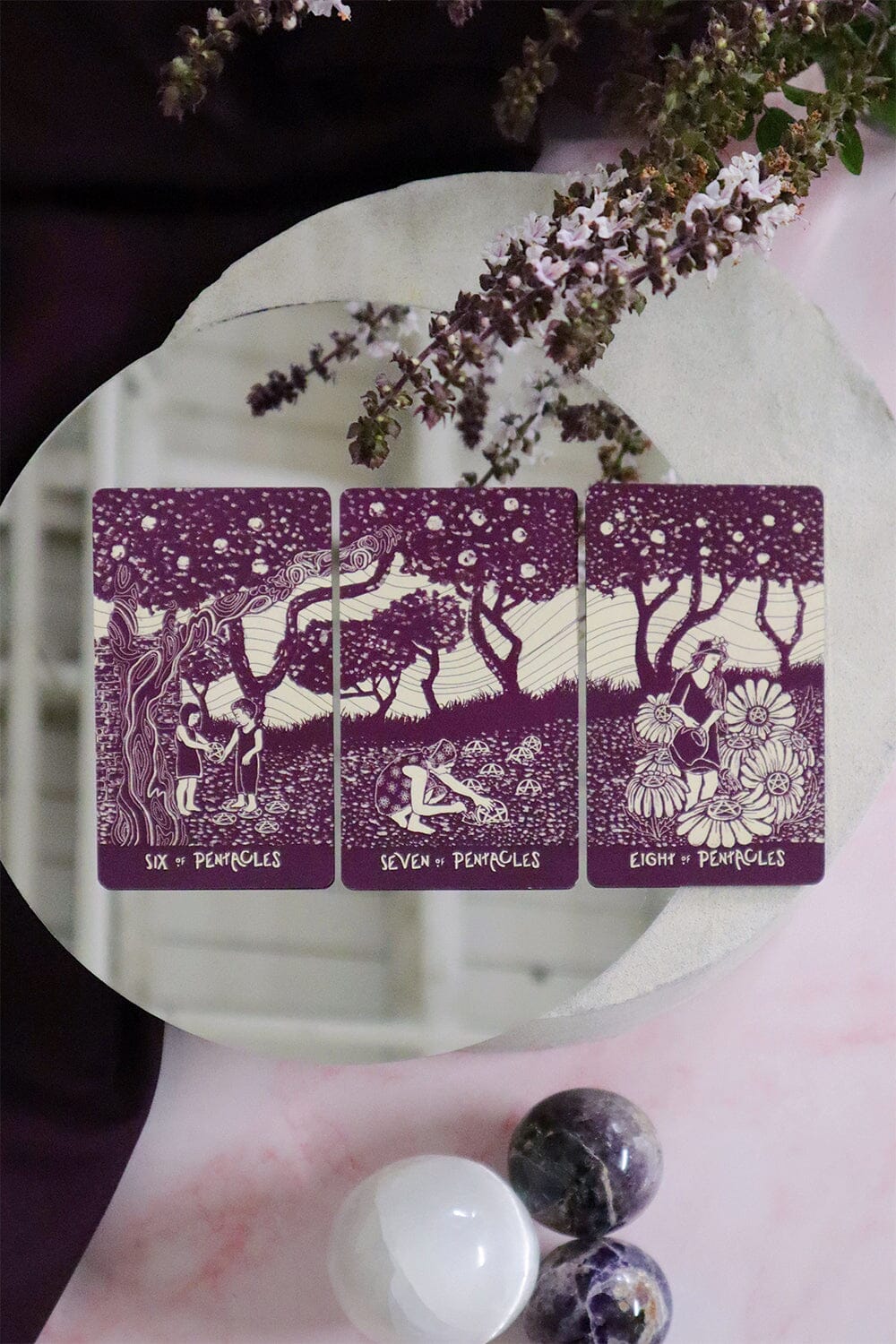 Three tarot cards with purple borders on a white surface with decorative elements.