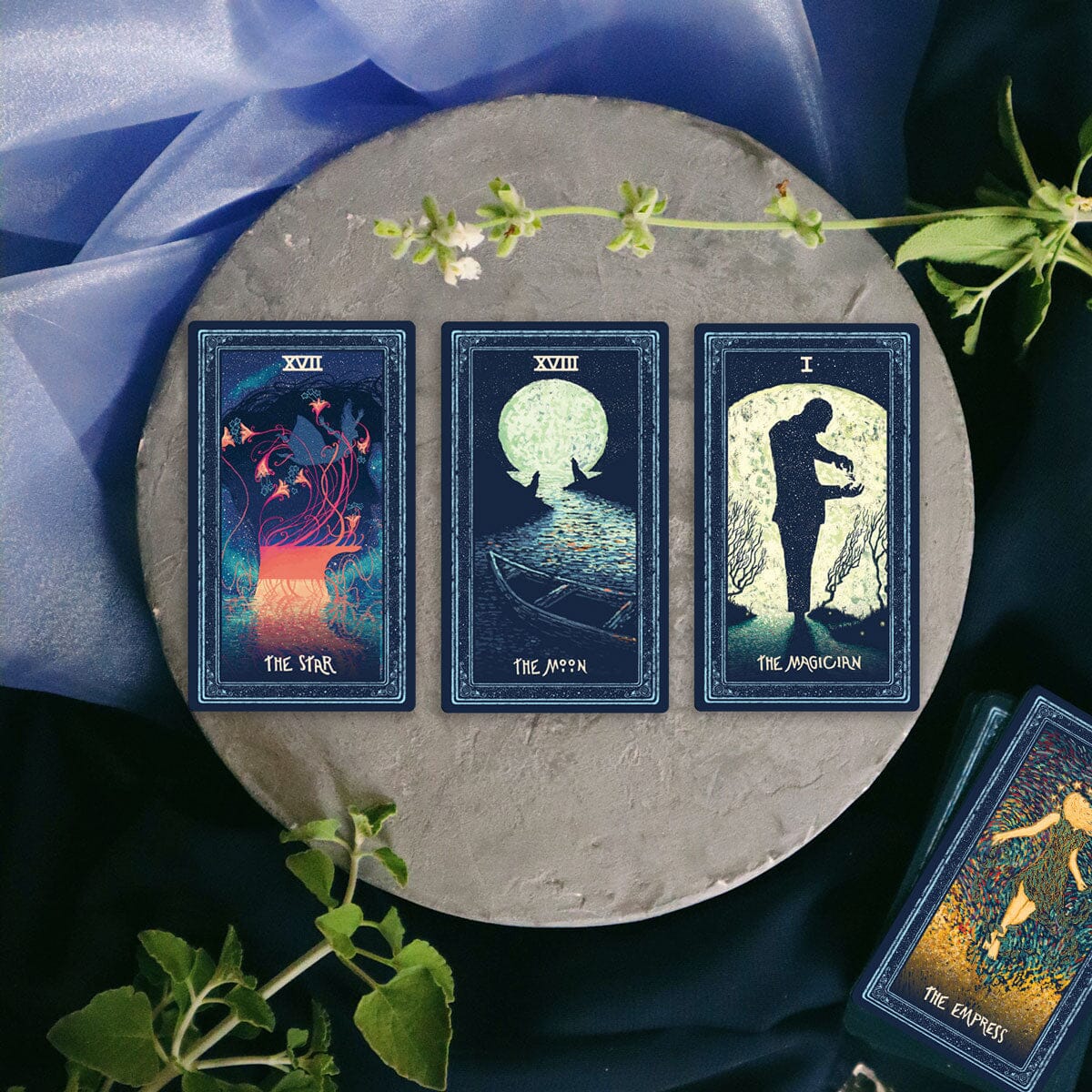 Three tarot cards on a round stone surface with plants around, against a dark background.