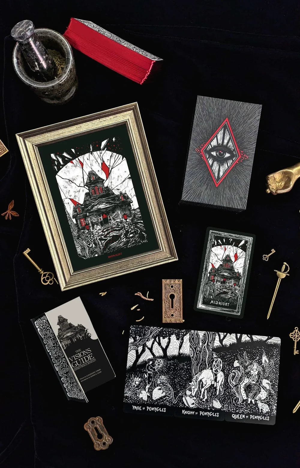 A flat-lay display of a gothic-themed tarot card deck and its accessories on a black background, including a gold-framed print, a red velvet box, a glass pestle and mortar, and several tarot cards with black and white illustrations featuring red accents.