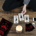 Person playing cards on a wooden table with a candle and phone.