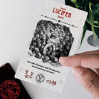 Card featuring 'Lucifer' with black and white illustration and text, held by a hand on a light background.