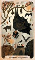 A tarot-style illustrated card titled 'The Autumn Hanged One' with the Roman numeral XII at the top. The artwork shows hanging bats, smaller bats flying, a bird, candles, leaves, rocks, and a skull on a muted beige background.