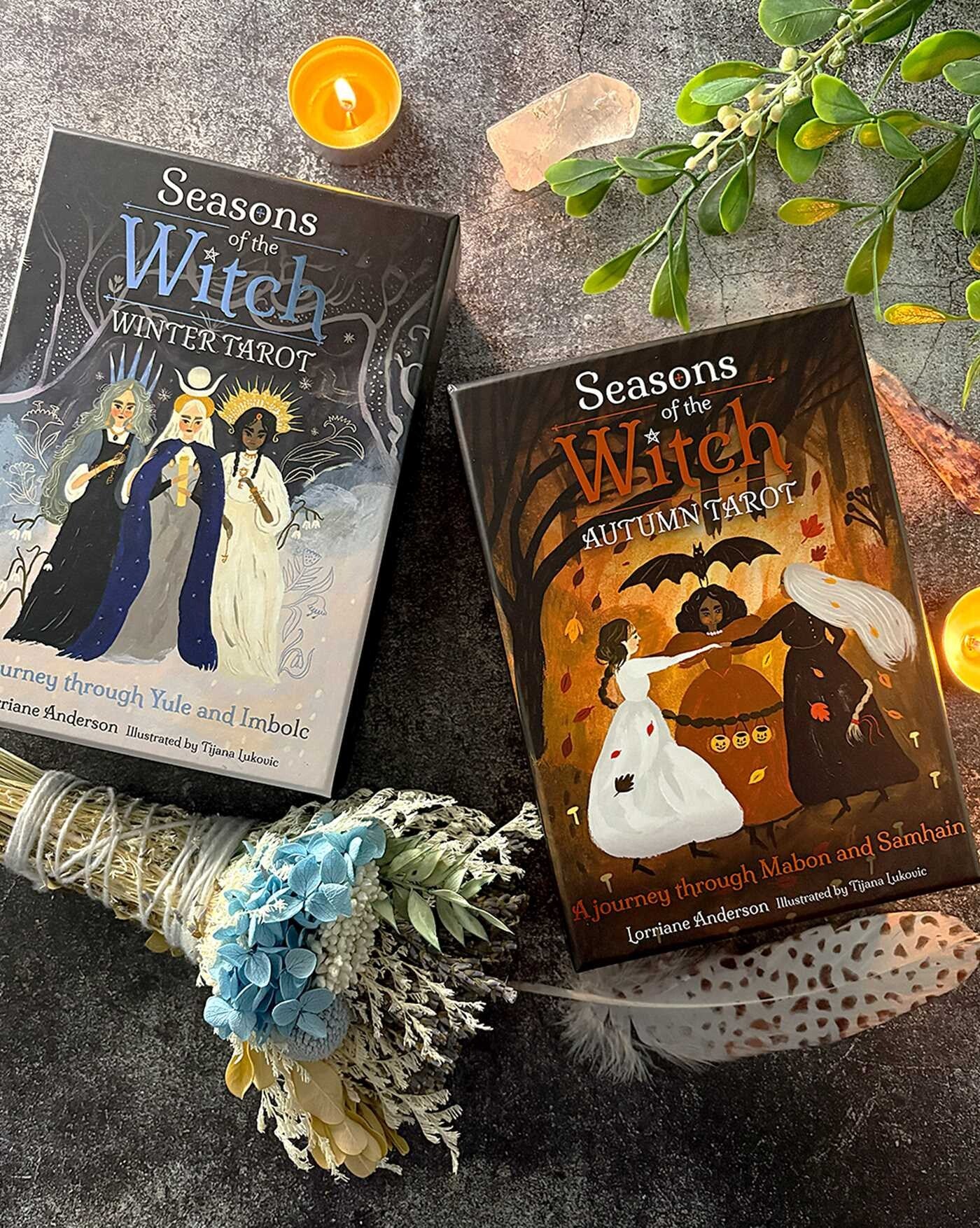 Two tarot books titled 'Seasons of the Witch' on a dark surface with decorative elements.