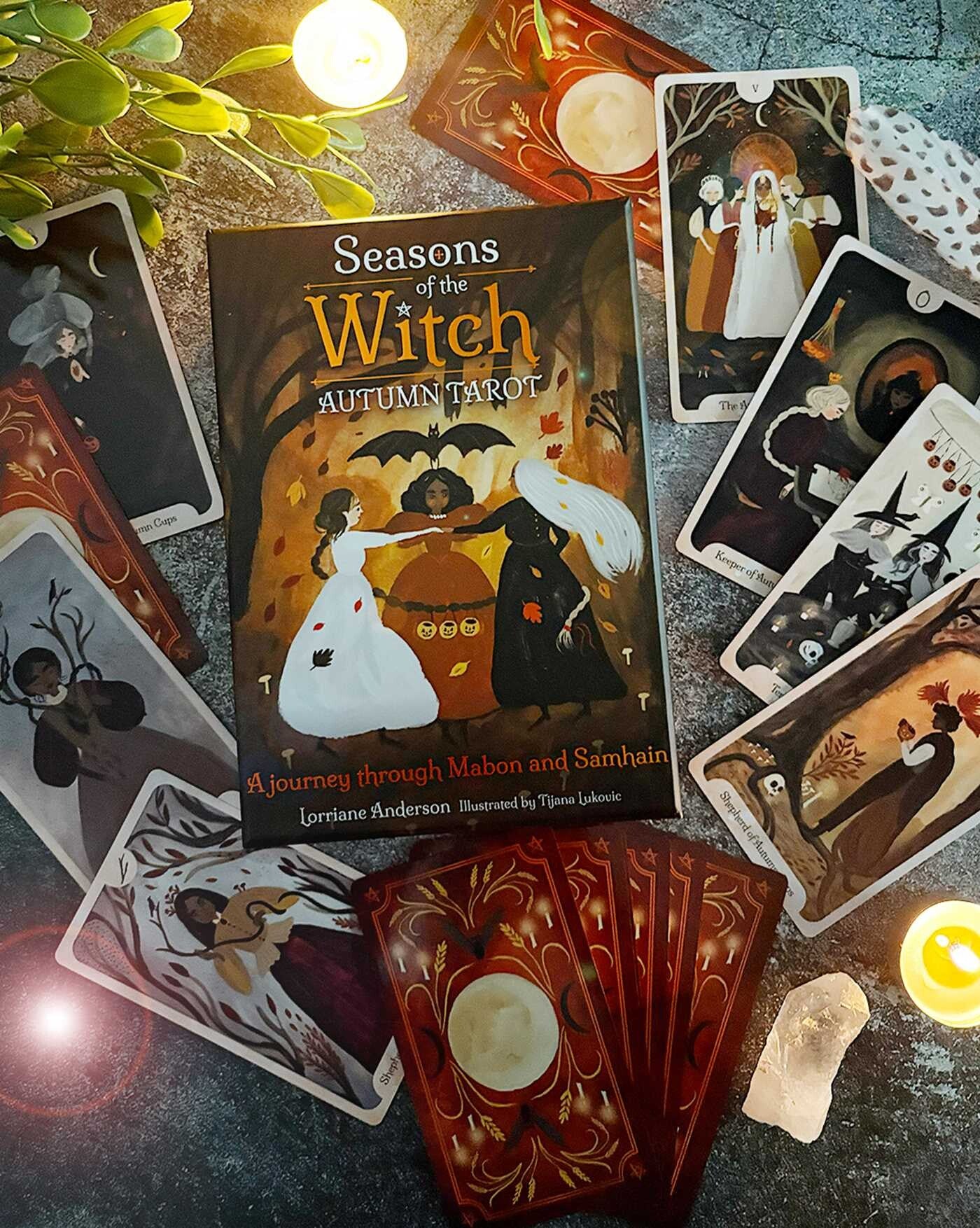 Tarot cards from 'Seasons of the Witch' Autumn Tarot set on a textured surface with candles and leaves.